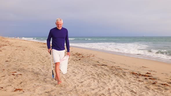 Mature Man Picking Up Trash At The Beach