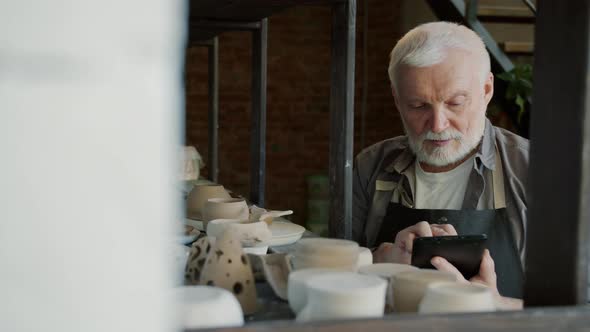 Slow Motion of Elderly Man Potter Using Tablet During Inventory in Workshop