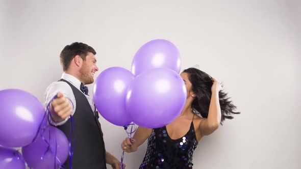 Happy Couple with Purple Balloons Dancing at Party