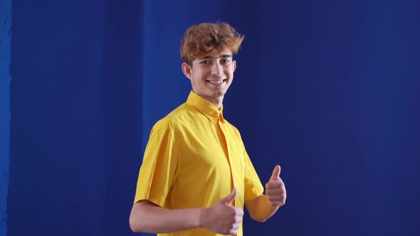 Portrait of a Happy Boy Pointing Fingers Up at Copy Space Isolated Over Blue Background