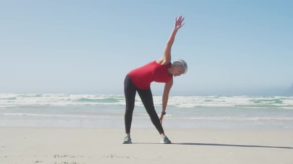 Senior woman stretching in the beach