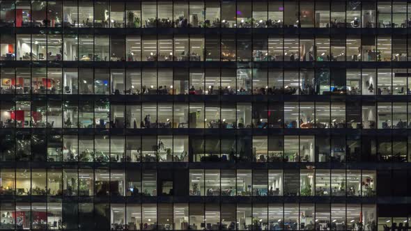 Panning to right view of office windows with working people