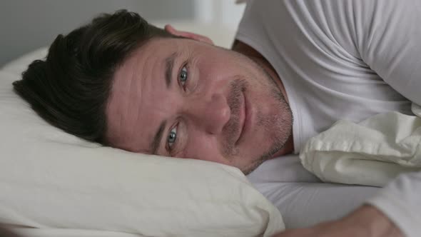 Middle Aged Man Laying in Bed Smiling at Camera 