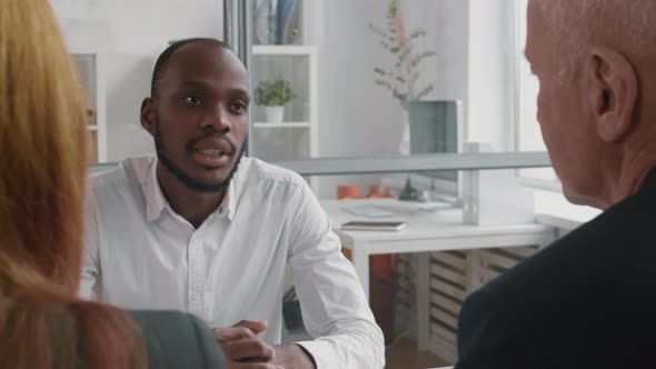 African Man Talking to Unrecognizable Colleagues