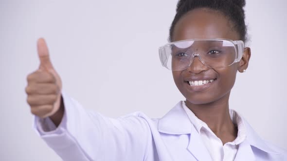 Face of Young Happy African Woman Doctor with Protective Glasses Giving Thumbs Up