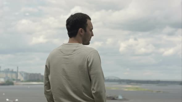 Young Man Is Looking Into the Distance To the River on a Cloudy Day