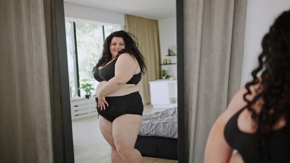 Young Plussize Woman in Underwear Examines Body in Mirror