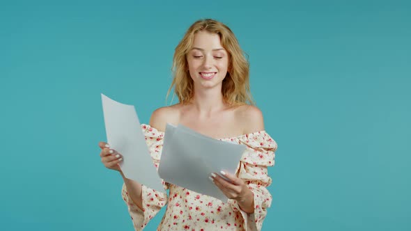 Pretty Girl Checks Documents, Utility Bills. Smiling Woman Standing on Blue Background. She Is