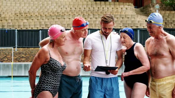 Swim coach training seniors on digital tablet