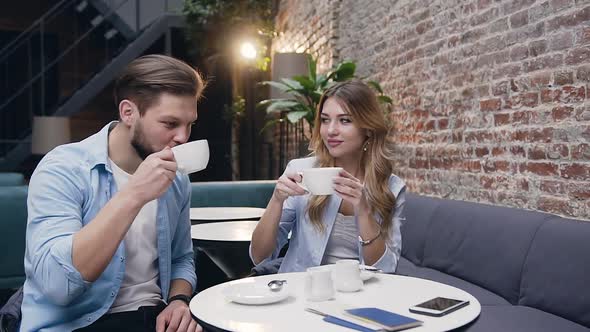 Amorated Satisfied Stylish Young People Sitting in the Hotel Lobby and Drinking Tea