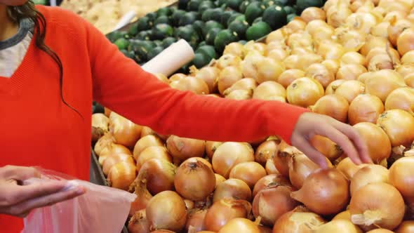 Woman buying onion in supermarket