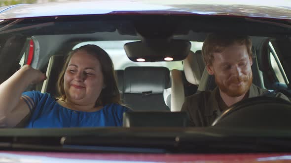 View Through Windscreen of Happy Young Parents Getting Out of Car Going for Children