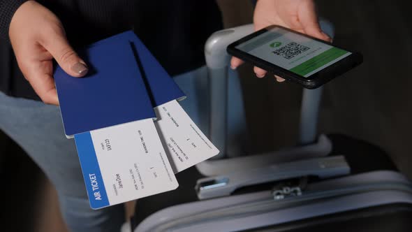 A Woman Holding a Phone with a QR Code and Passports with Tickets at the Airport