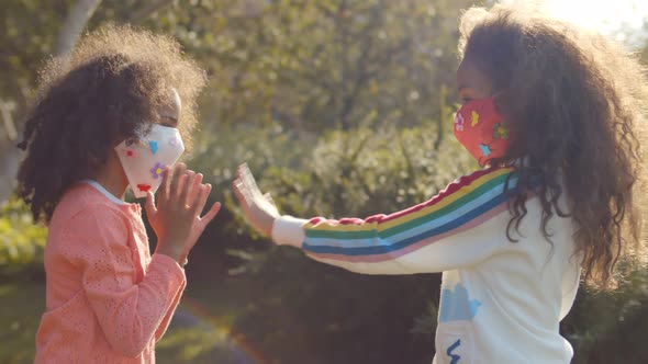 Two Afro Girls in Safety Mask Playing Hand Clapping Game Outdoors