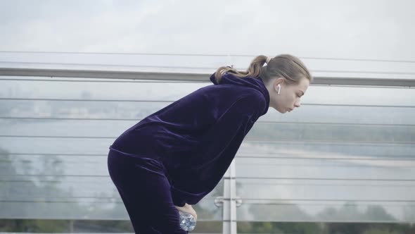 Exhausted Caucasian Sportswoman Standing on Bridge Breathing in and Out