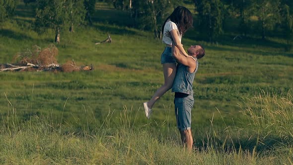 Handsome Man in Denim Vest and Shorts Lifts Brunette Lady