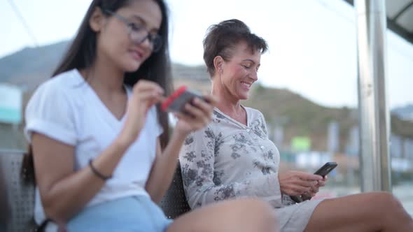 Mature Tourist Woman Using Phone While Waiting For The Train With Young Asian Tourist Woman