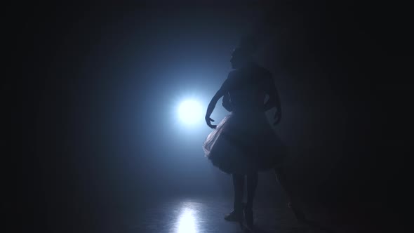 Silhouette of Young Man Practicing in Classical Ballet Pirouette with Ballerina on Dark Smoke Studio