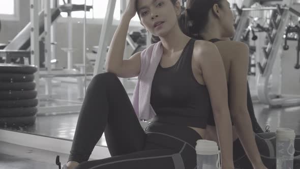 Beautiful young asian woman after workout with tired and exhausted in the gym.