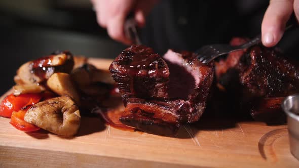 cutting beef steak with a knife on a wooden board