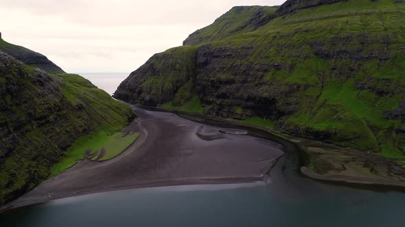 Aerial view of river passing between rock formation cliff, Faroe island.
