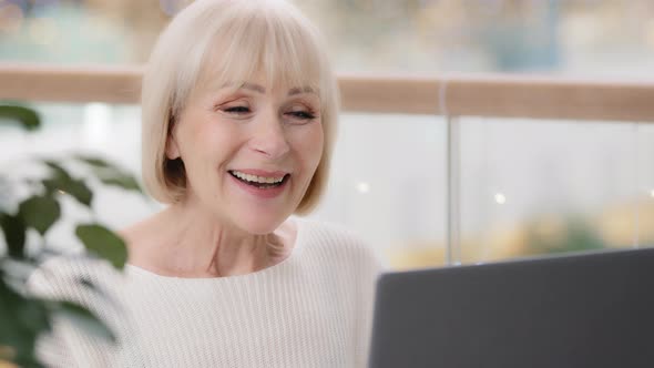Closeup Mature Cute Caucasian Woman Communicates Video Chatting Looking at Laptop Screen Waving