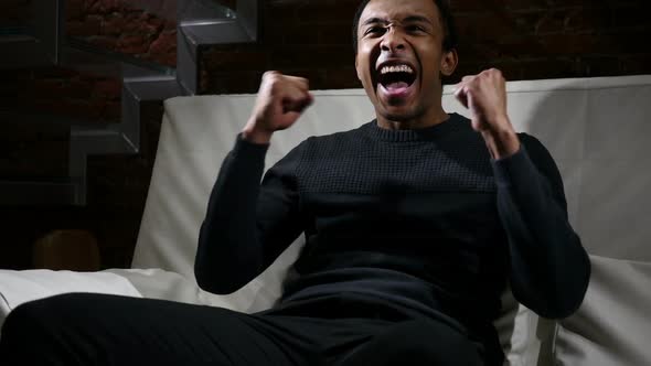 African Man Watching Match on TV and Celebrating Team Success