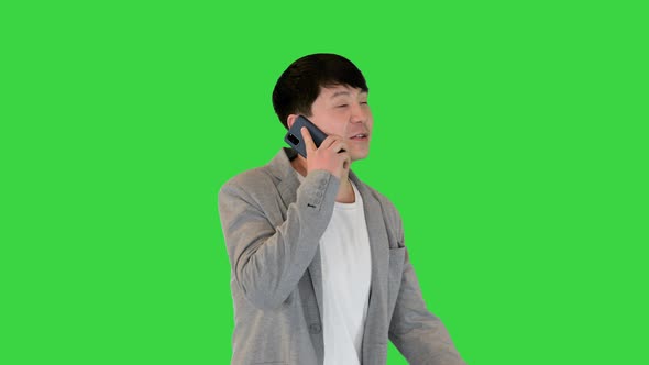 Young Asian Man Makes a Short Call with His Smartphone on a Green Screen Chroma Key