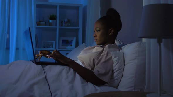 African Woman Using Laptop in Bed at Home at Night