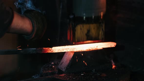 Closeup of Hydraulic Hammer Shaping Piece of Hot Iron. Blacksmith Making Blades for Knifes in His