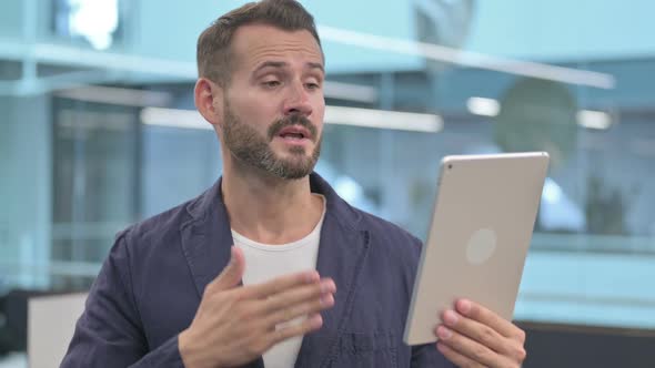 Video Call on Tablet By Middle Aged Businessman in Office