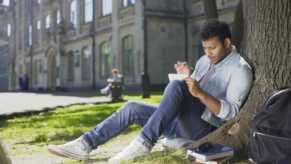 University Student Sitting Under Tree on Campus, Solving Task in Notebook, Smart