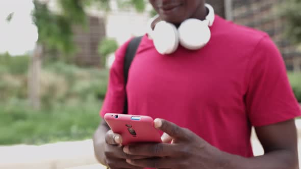 Happy African American Delivery Man Using Mobile Phone in the Street