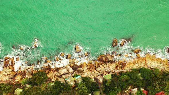 Beautiful rocky coast Koh Phangan, Thailand. Emerald wavy sea washing rocks on the island edge