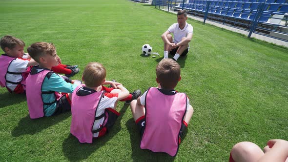 Young Boys Team on the Training Football Field, the Coach Instructs and Trains Young Players in