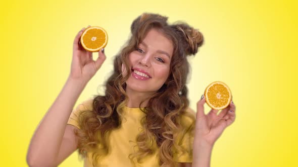 Attractive Girl in a Yellow Shirt Posing with Oranges and Smiling While Looking at the Camera