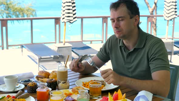 Happy Man Have Breakfast at Luxury Restaurant in Tropical Hotel with Turquoise Sea Background