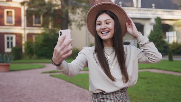 Smiling Beautiful Young Woman in Beige Hat which Talking on Phone Video Chat