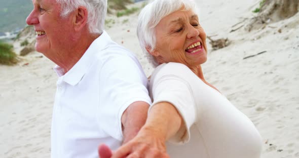 Senior couple standing back to back with arms outstretched