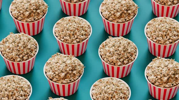 Animation of jumping buckets full of popcorn. Tasty snack on a blue background.