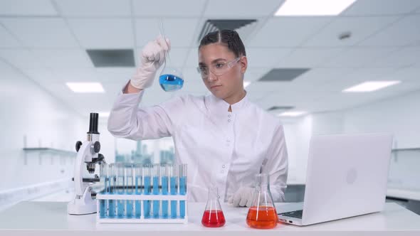 A Female Researcher Analyzes the Liquid in the Flask and Does Clinical Trials. Female Scientist