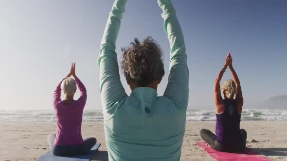 Athletic women performing yoga in the beach