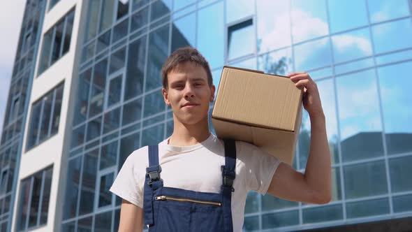 A Delivery Worker Holds a Box on His Shoulder Looking at the Camera and Then Walks to the Side