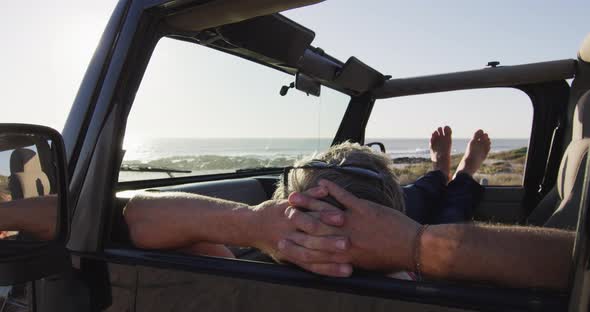 Relaxed caucasian man lying in car resting on sunny day at the beach