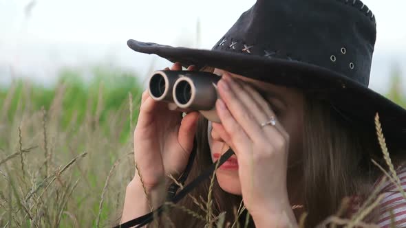 Beautiful Young Girl Looking Through Binoculars On Blue Sky Background.