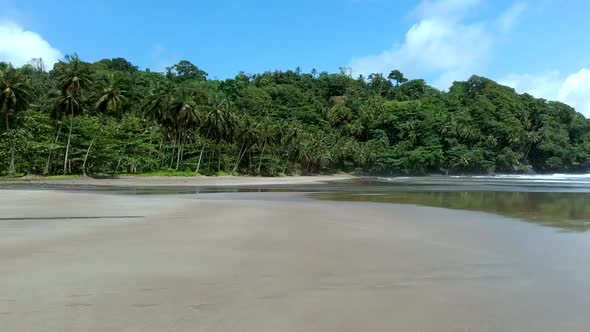 Aerial along empty black sand beach with mirror effect, São Tomé Island