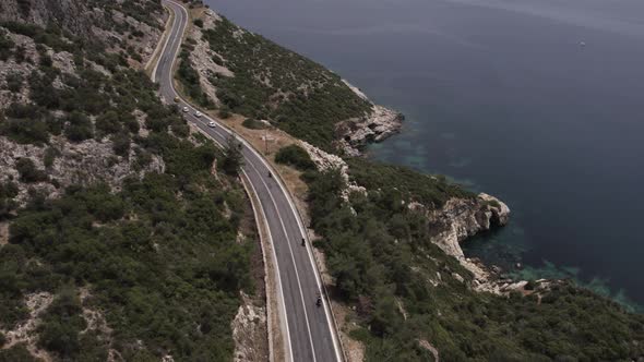 aerial shot, motorcyclist at sunset through beach side and mountains. amazing lovely view. road trip