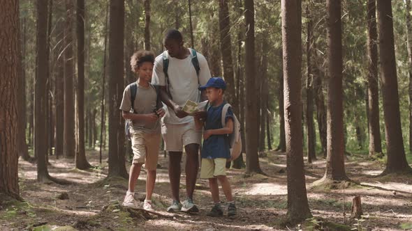 Dad and Sons Walking through Forest with Map