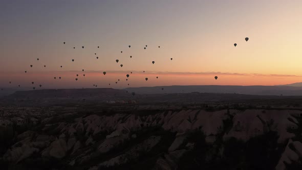 Colorful Hot Air Balloons Flying Over Rocky Landscape at Sunset Sky