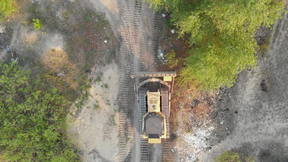 Top Aerial View on Tracked Bulldozer Rides on Sandy Road at Construction Site